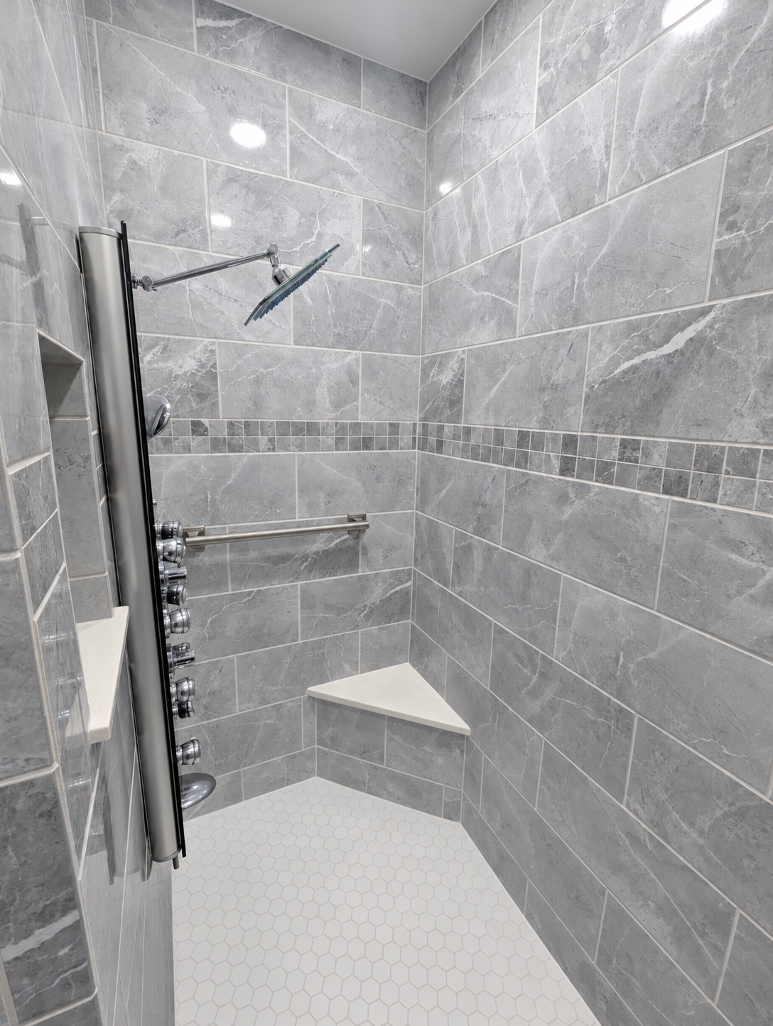 Gray marble-look tiled shower with a corner bench and mosaic floor